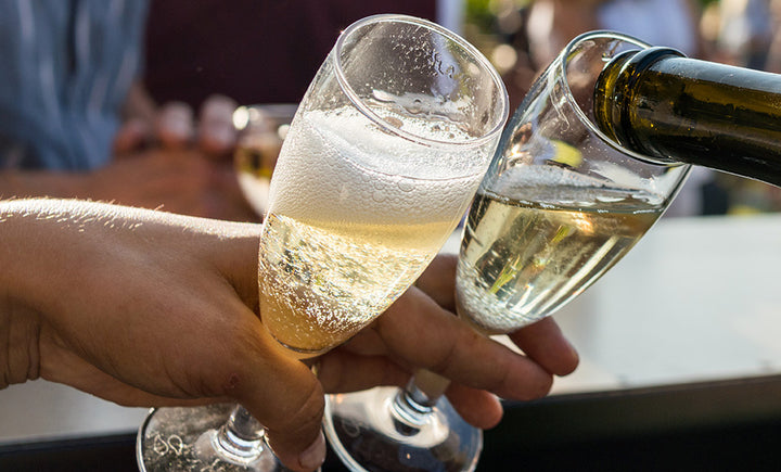 Chilworth Manor sparkling white wine poured into flutes held by guests during an outdoor English vineyard tasting event in surrey